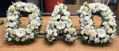 Loose Letters - A beautiful personalised letter tribute created to honour a loved one with elegance, dignity, and heartfelt remembrance. Designed in a timeless all-white palette, this handcrafted arrangement offers a graceful expression of sympathy and serves as a meaningful focal point during funeral and memorial services.

Each letter is carefully arranged with fresh seasonal blooms and delicate foliage, creating a refined and respectful tribute that celebrates a life cherished and never forgotten. Ideal for spelling initials, names, or special words that hold personal significance.